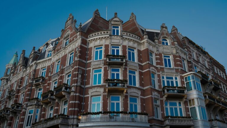 Charming historic hotel facade in Amsterdam with festive decorations, bright windows, and classic architecture.