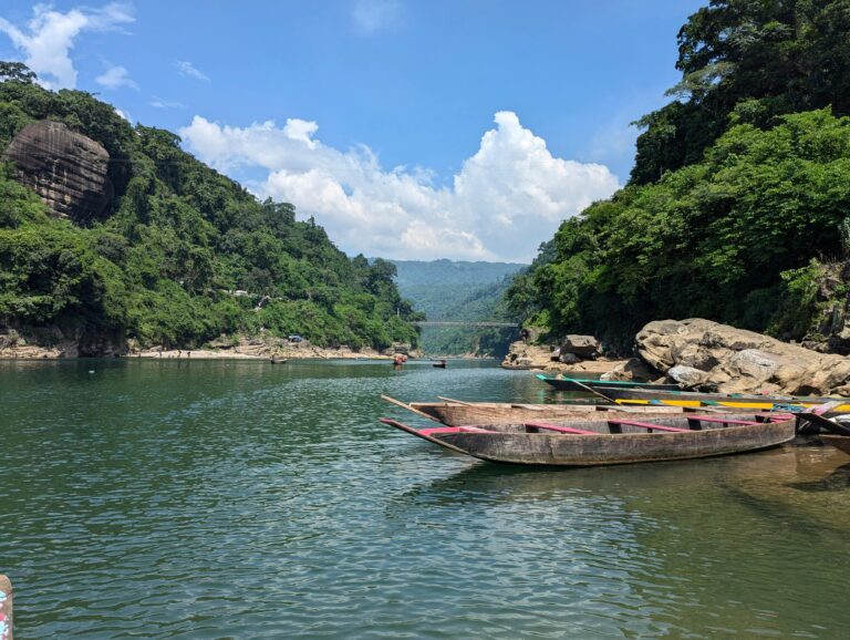 Scenic view of boats on turquoise waters with lush hills in Meghalaya, India.